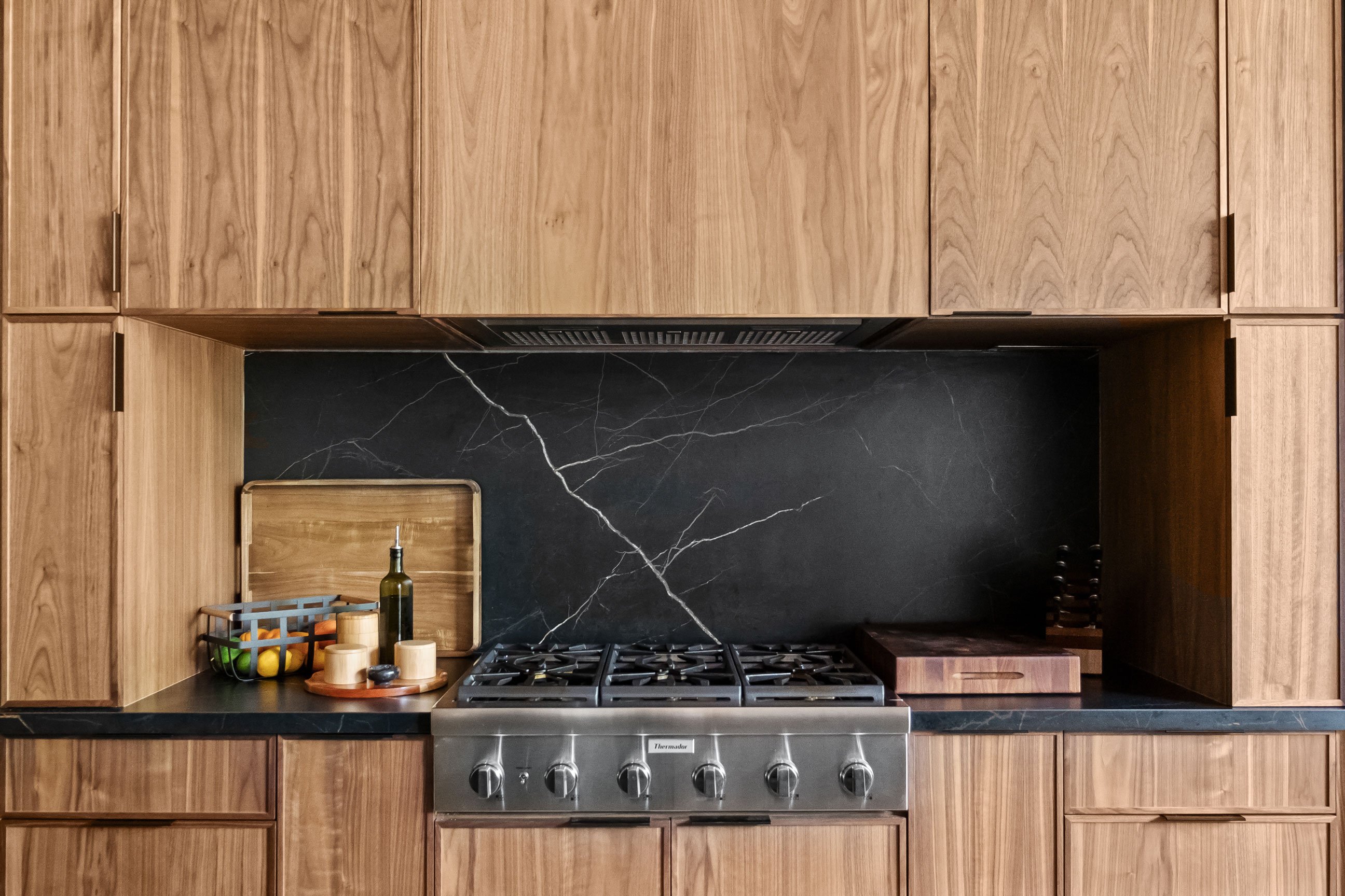 Contemporary loft kitchen featuring natural walnut and black-painted Inspira Cabinetry - range detail