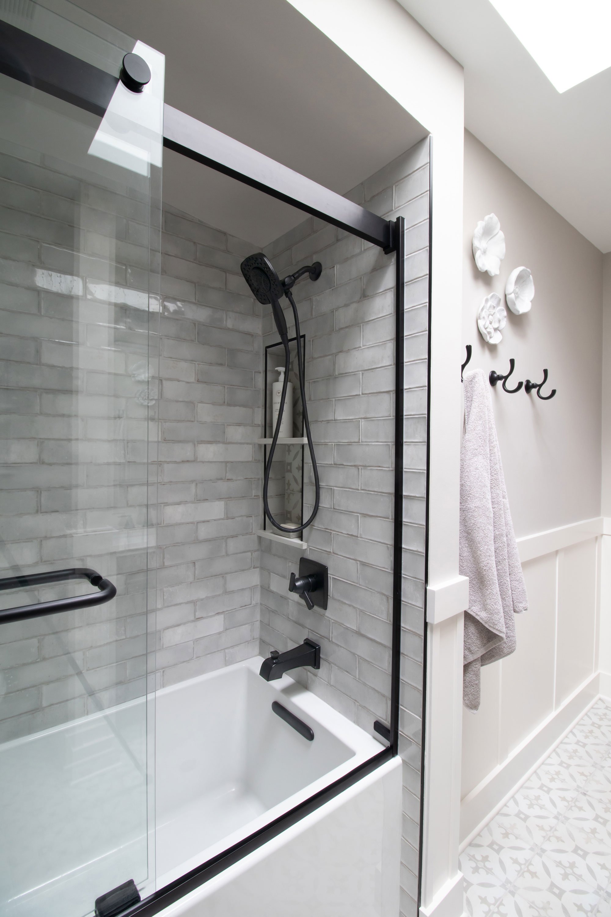 Hackney Pearl 3x9 tile (field) with Decora Redondo (niche), Kohler Underscore Tub, Kohler Levity Shower Doors, Delta Ashlyn Series Matte Black fixtures
