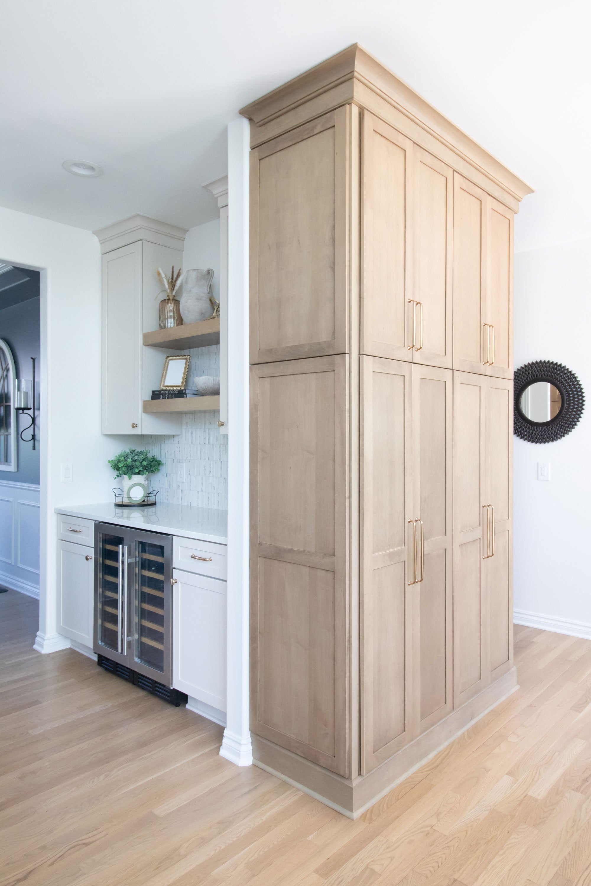 Cabinetry: Merillat Masterpiece Martel Door in Cottage Paint and Maple with Wicker Stain; Countertops: French Lace Quartz; Tile: Artistic Tile Abbey Road Calacatta Gold Marble Mosaic, honed