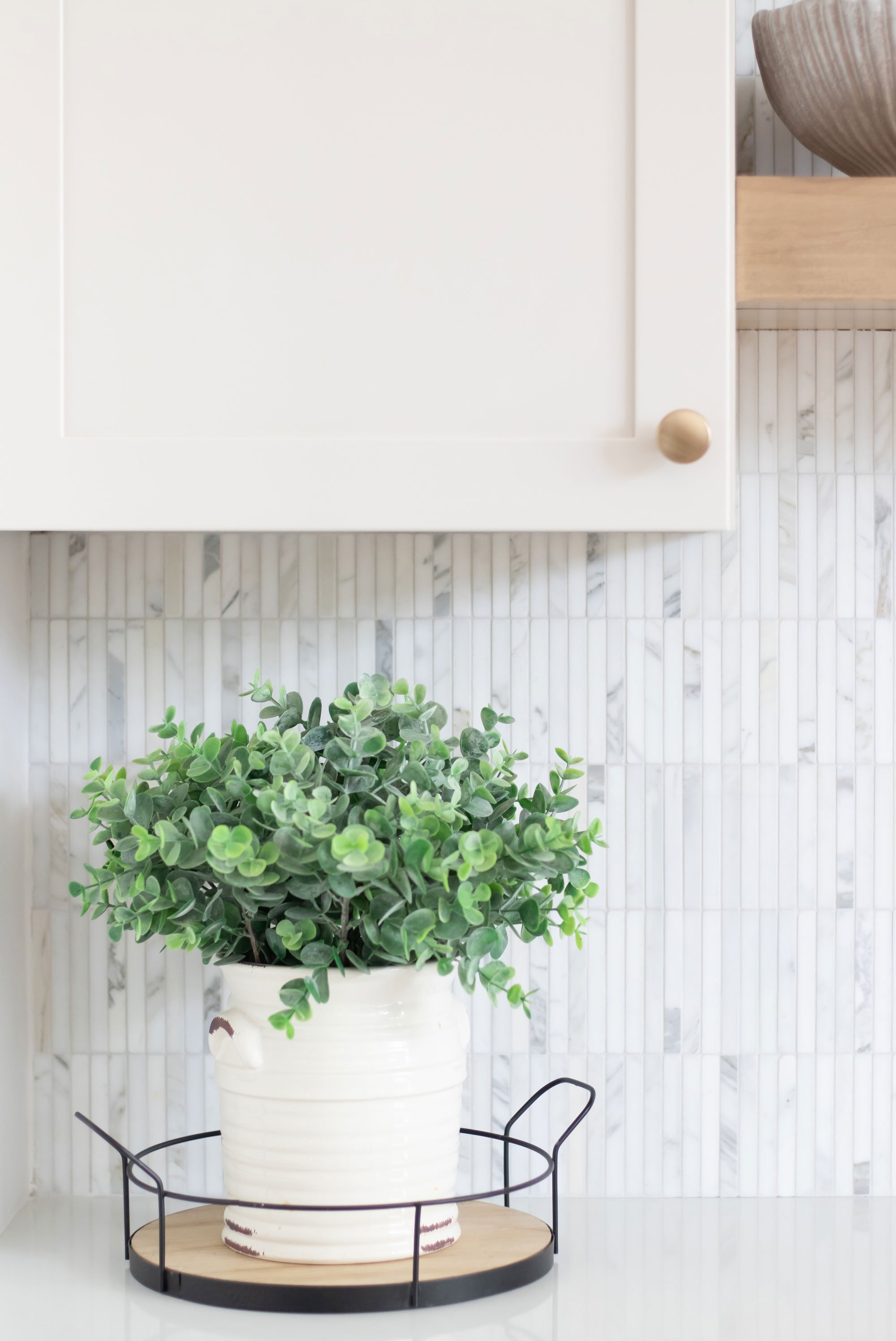 Cabinetry: Merillat Masterpiece Martel Door in Cottage Paint; Countertops: French Lace Quartz; Tile: Artistic Tile Abbey Road Calacatta Gold Marble Mosaic, honed
