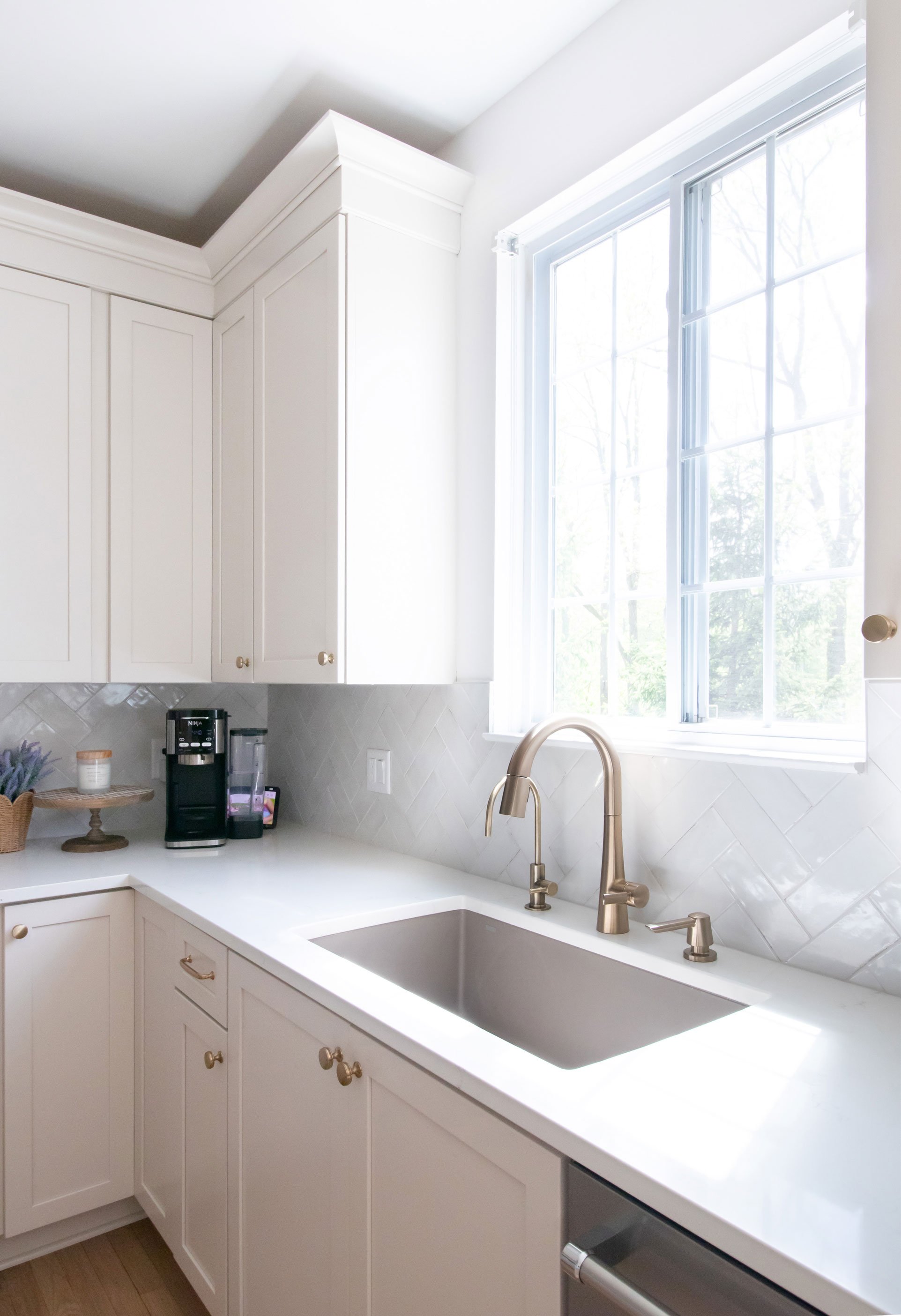 Cabinetry: Merillat Masterpiece Martel Door in Cottage Paint; Countertops: French Lace Quartz; Tile: Marazzi Rice Bianco 3x8 in herringbone pattern