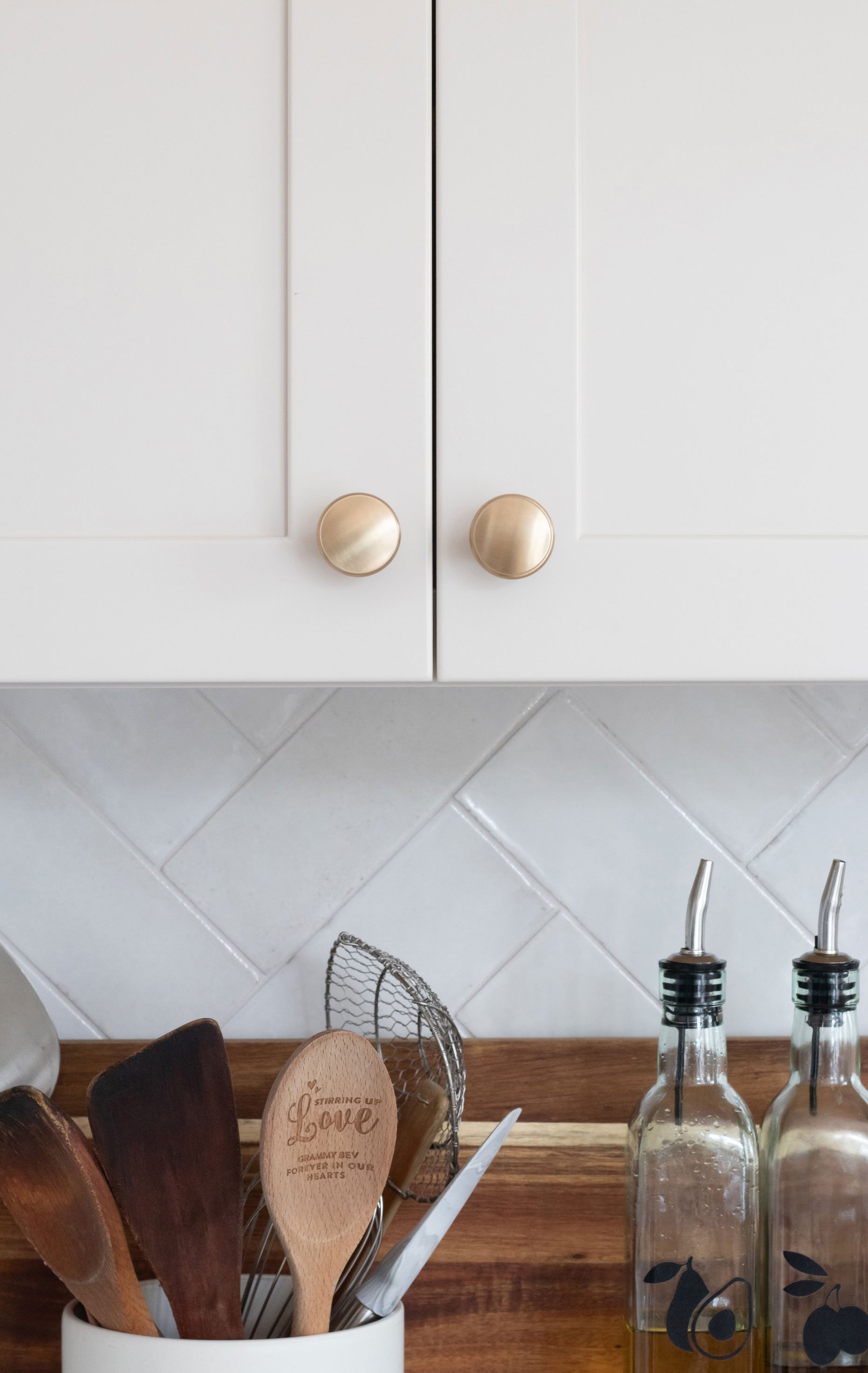 Cabinetry: Merillat Masterpiece Martel Door in Cottage Paint; Countertops: French Lace Quartz; Tile: Marazzi Rice Bianco 3x8 in herringbone pattern