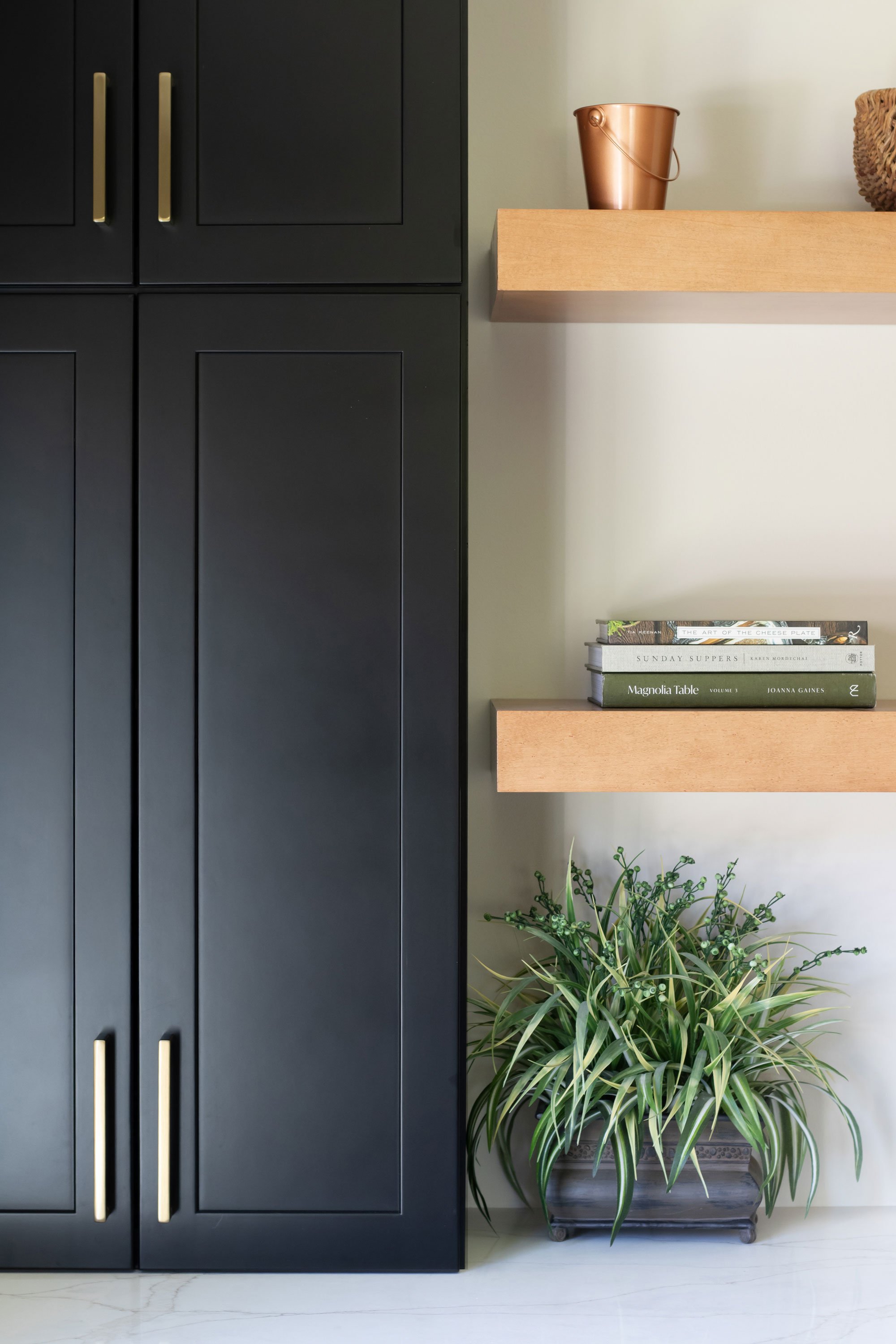 Black cabinetry detail with warm wood shelves on white quartz countertop